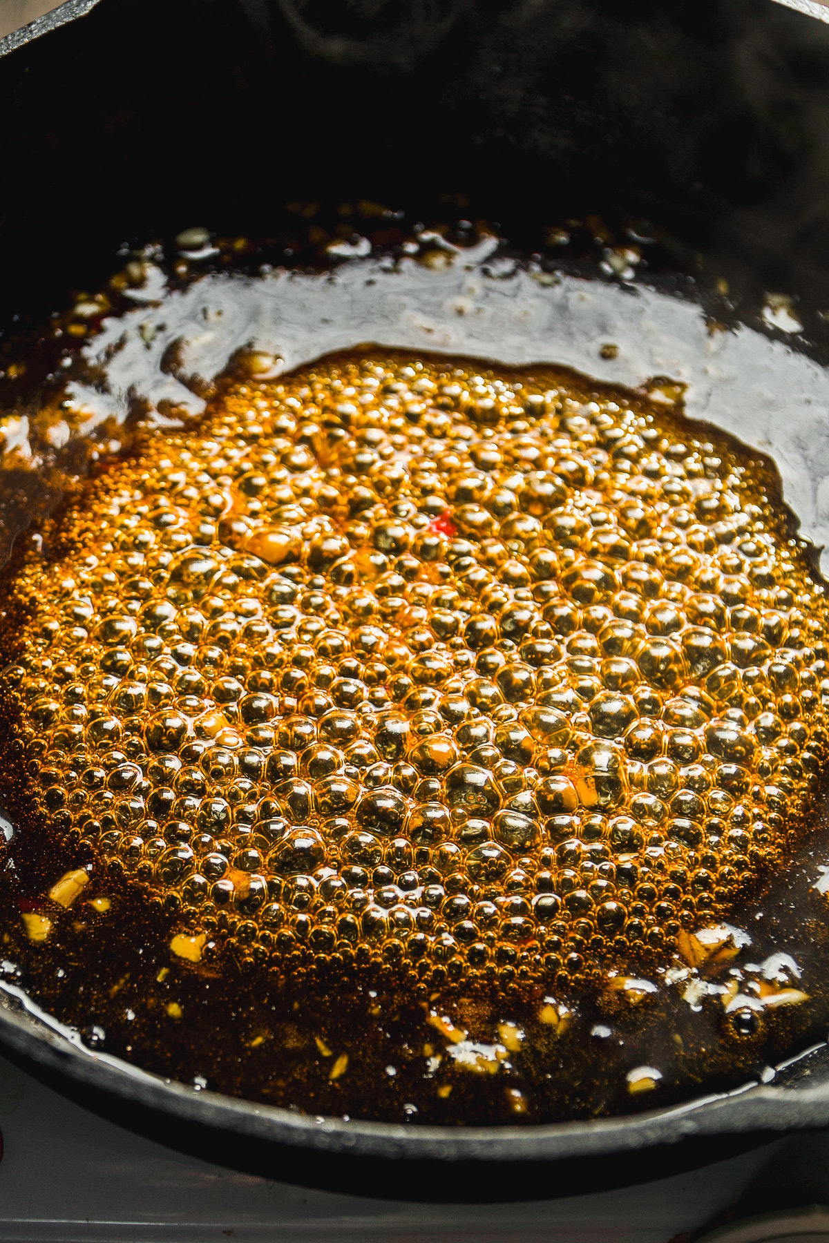 Honey chili sauce sizzling in a black skillet.
