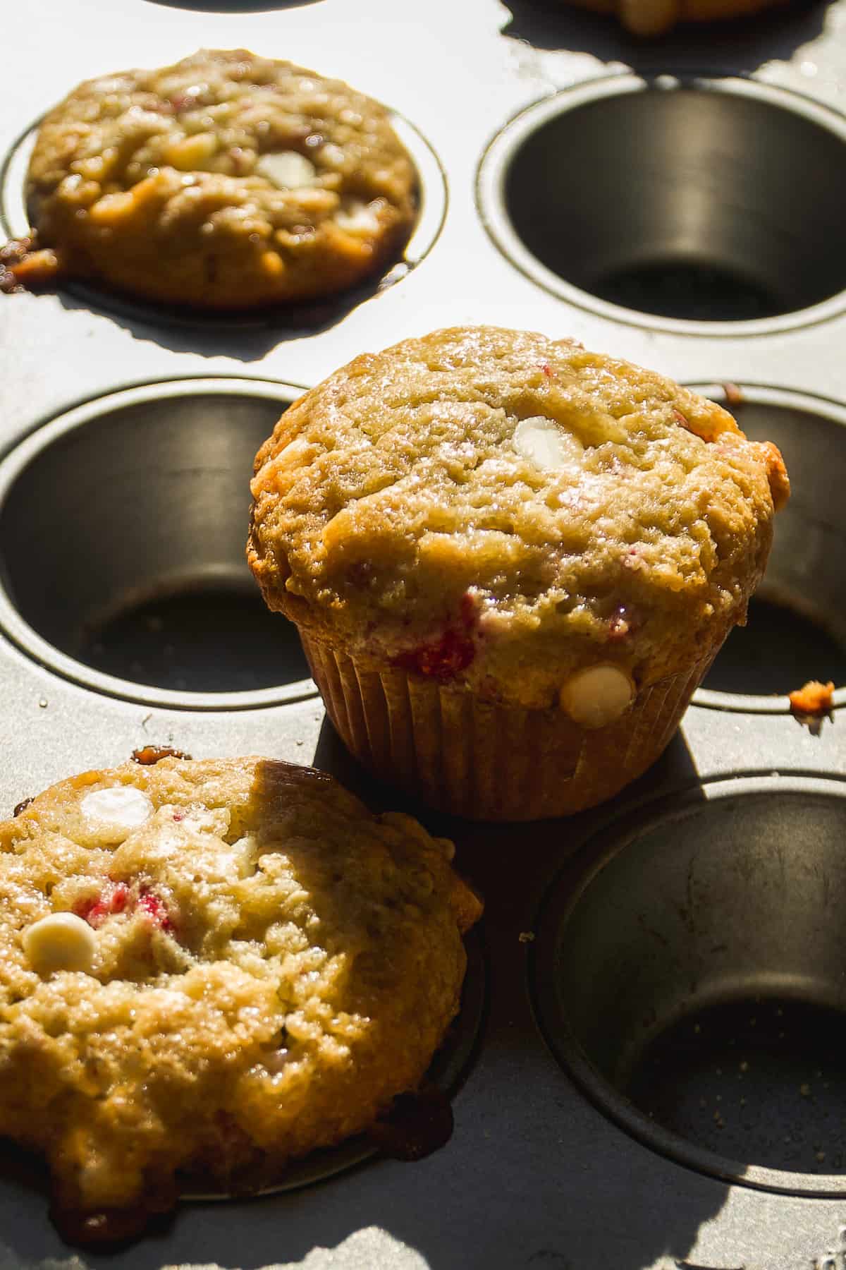 White chocolate raspberry muffins baked on a muffin pan.