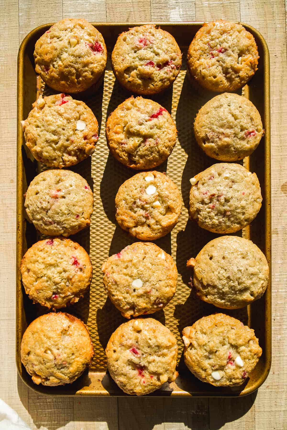 Raspberry white chocolate muffins baked on a pan.