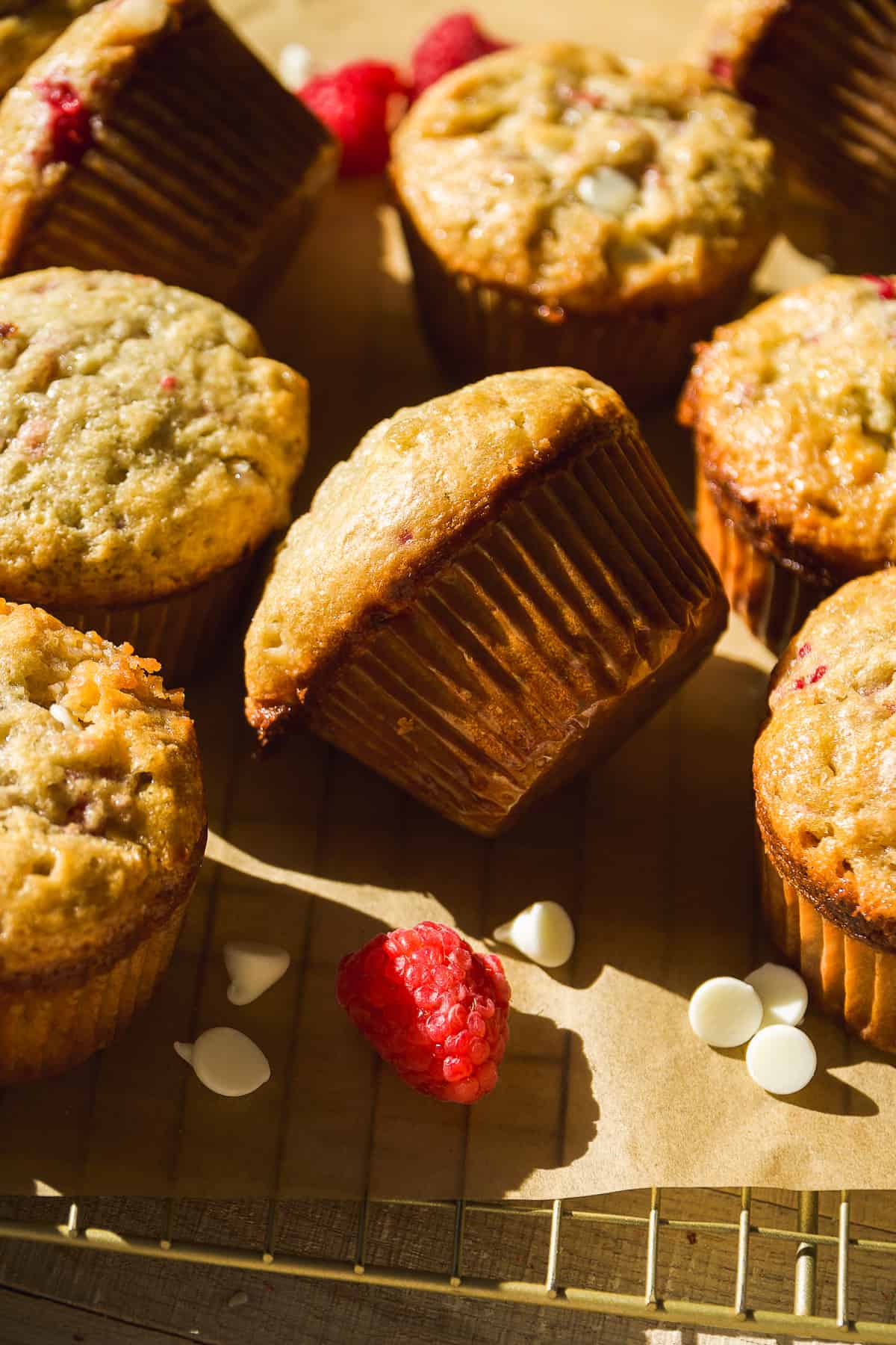 Raspberry white chocolate muffins scattered on a cooling rack.