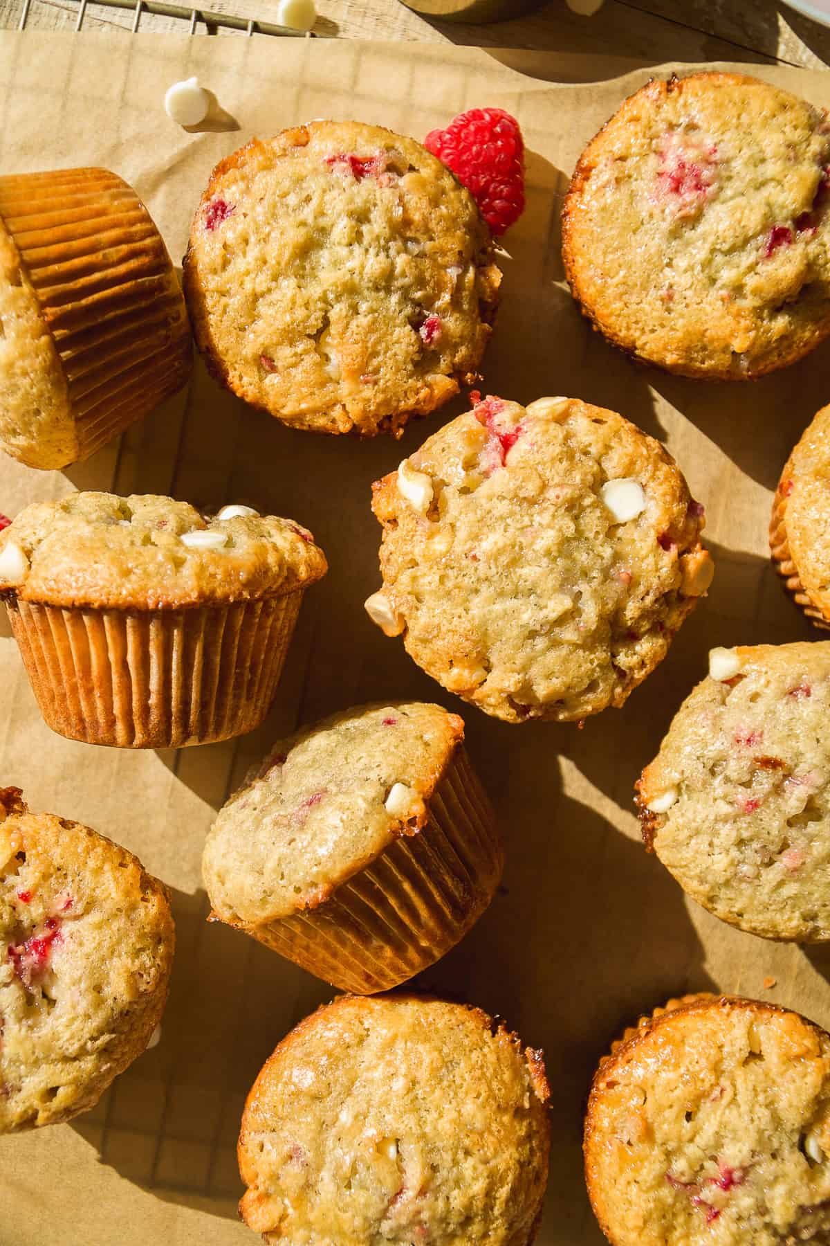 Raspberry white chocolate muffins scattered on a wire rack.