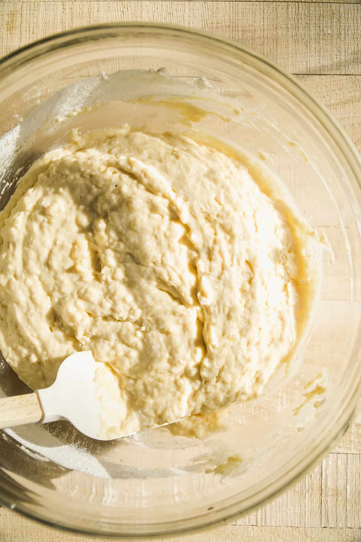 Muffin batter in a glass bowl with a spatula.