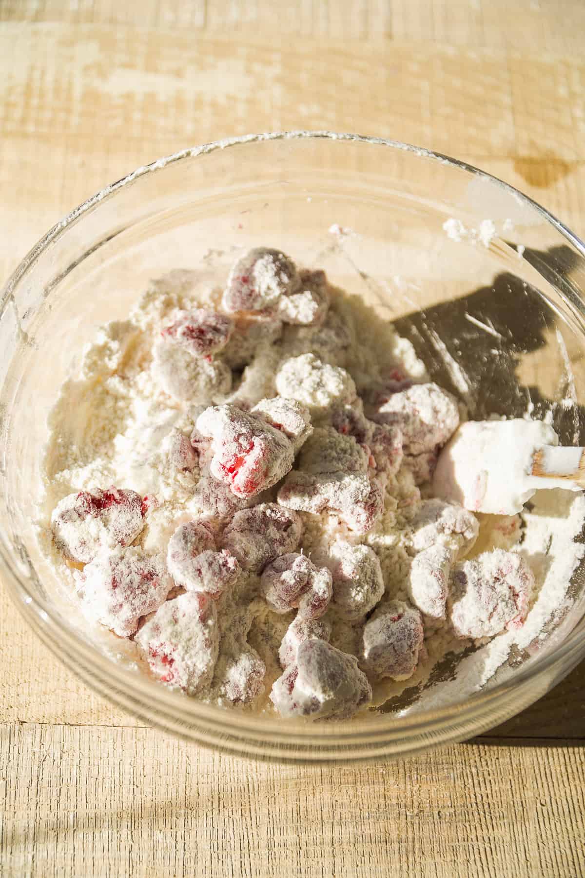 Raspberries coated in flour in a glass bowl.