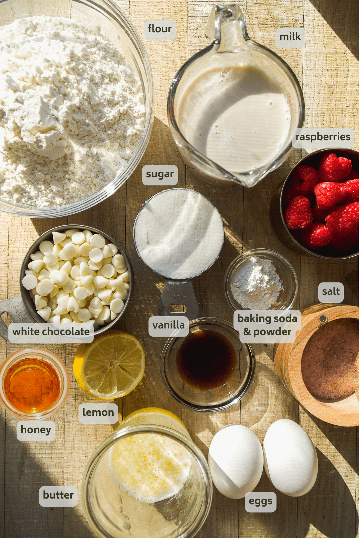 Raspberry white chocolate muffin ingredients on a wooden surface.