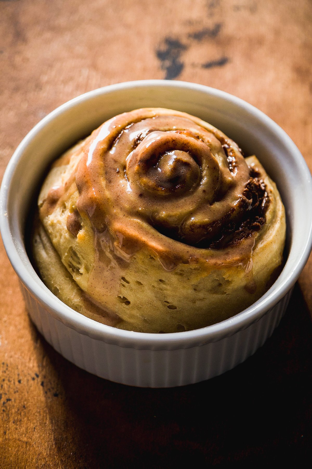 Single serve cinnamon roll with icing in a ramekin.