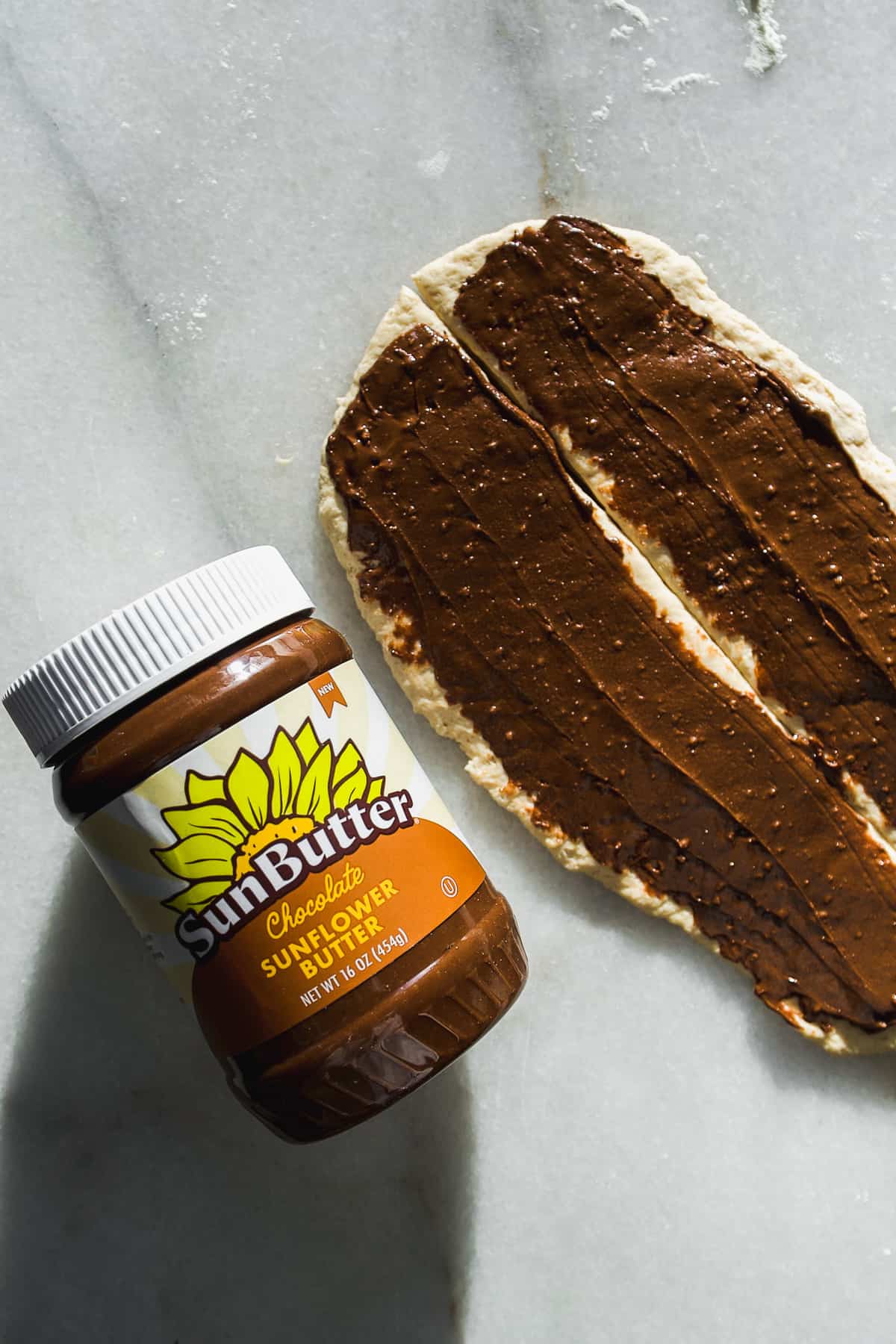 Chocolate SunButter spread on top of two strips of dough.