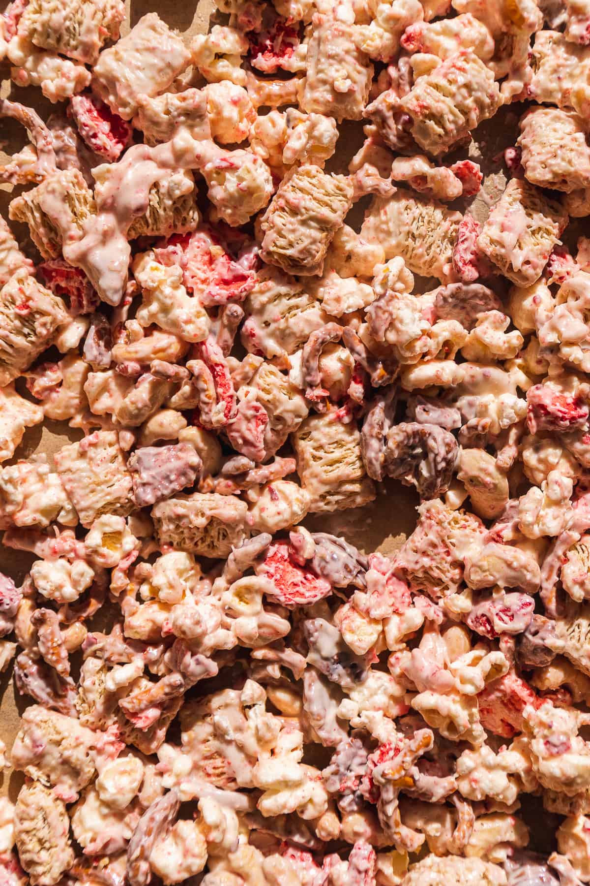 Valentine snack mix with white chocolate and strawberries on parchment paper.