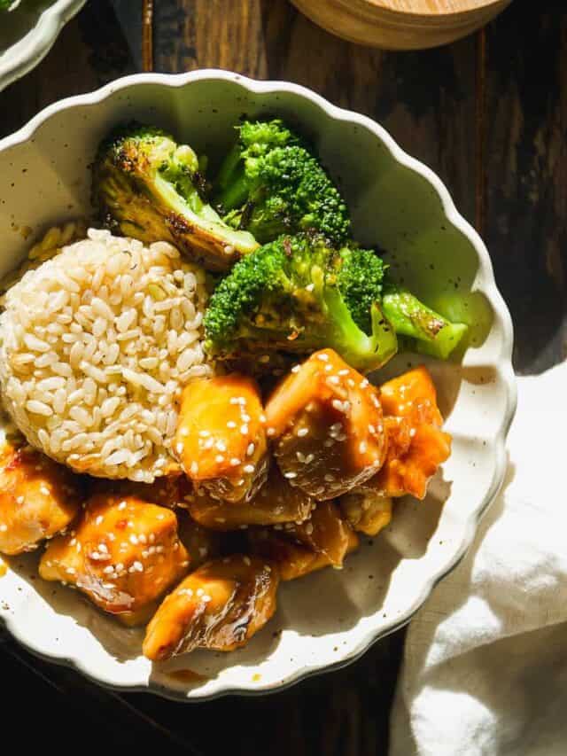 Honey sesame chicken in a bowl with rice and broccoli.