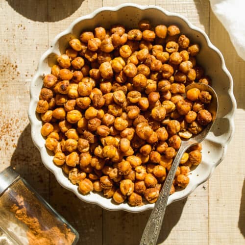 Cinnamon sugar roasted chickpeas in a bowl with cinnamon dusted on the surface.