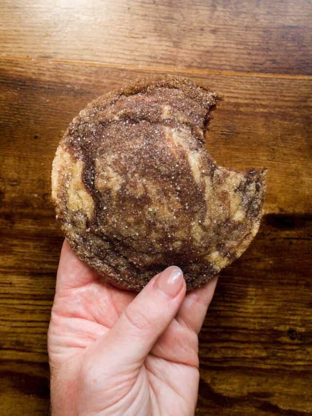 Person holding marbled cookie with sugar.