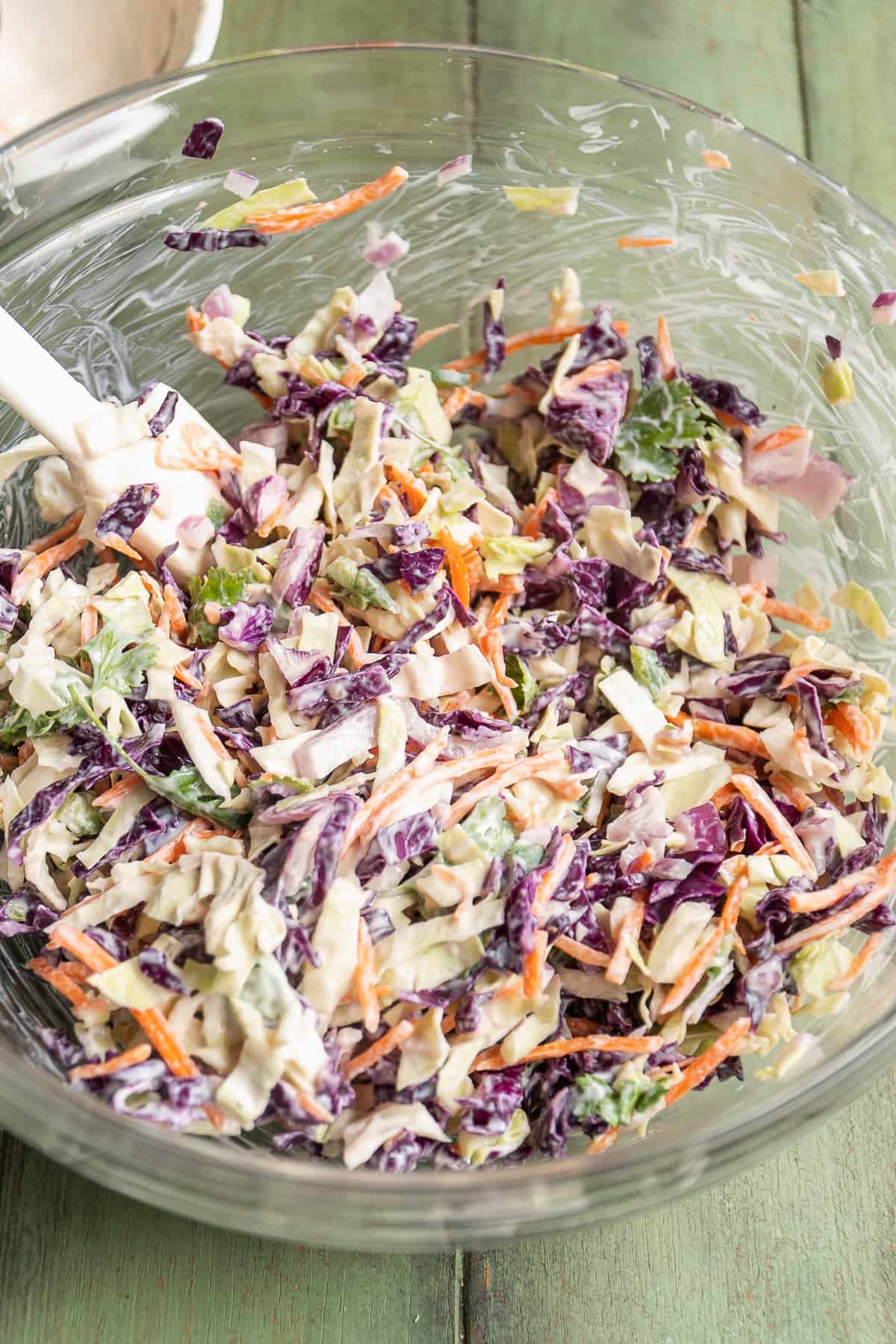 Coleslaw mixed in a glass bowl with yogurt sauce.