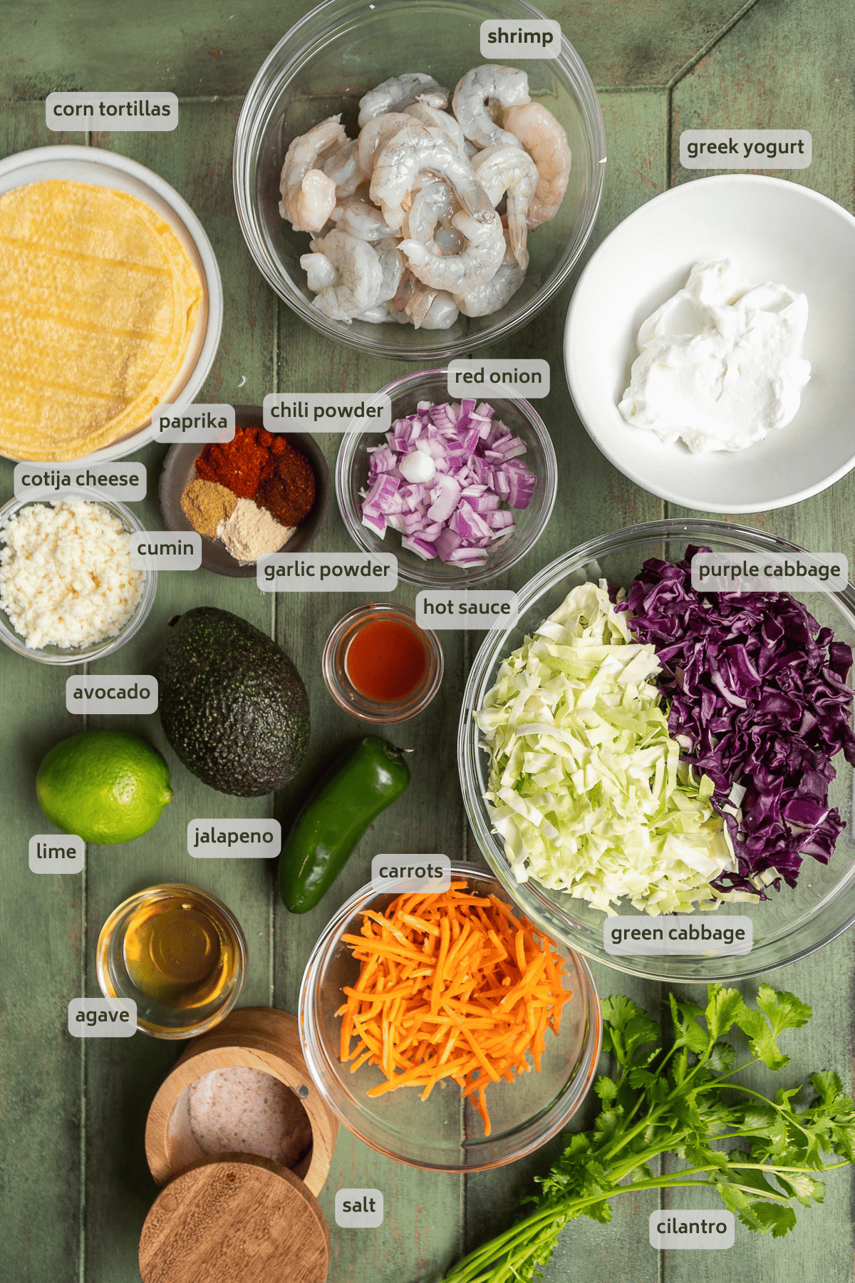 Baja shrimp taco ingredients on a green surface.