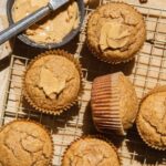 Peanut butter banana almond flour muffins scattered on a wooden surface.