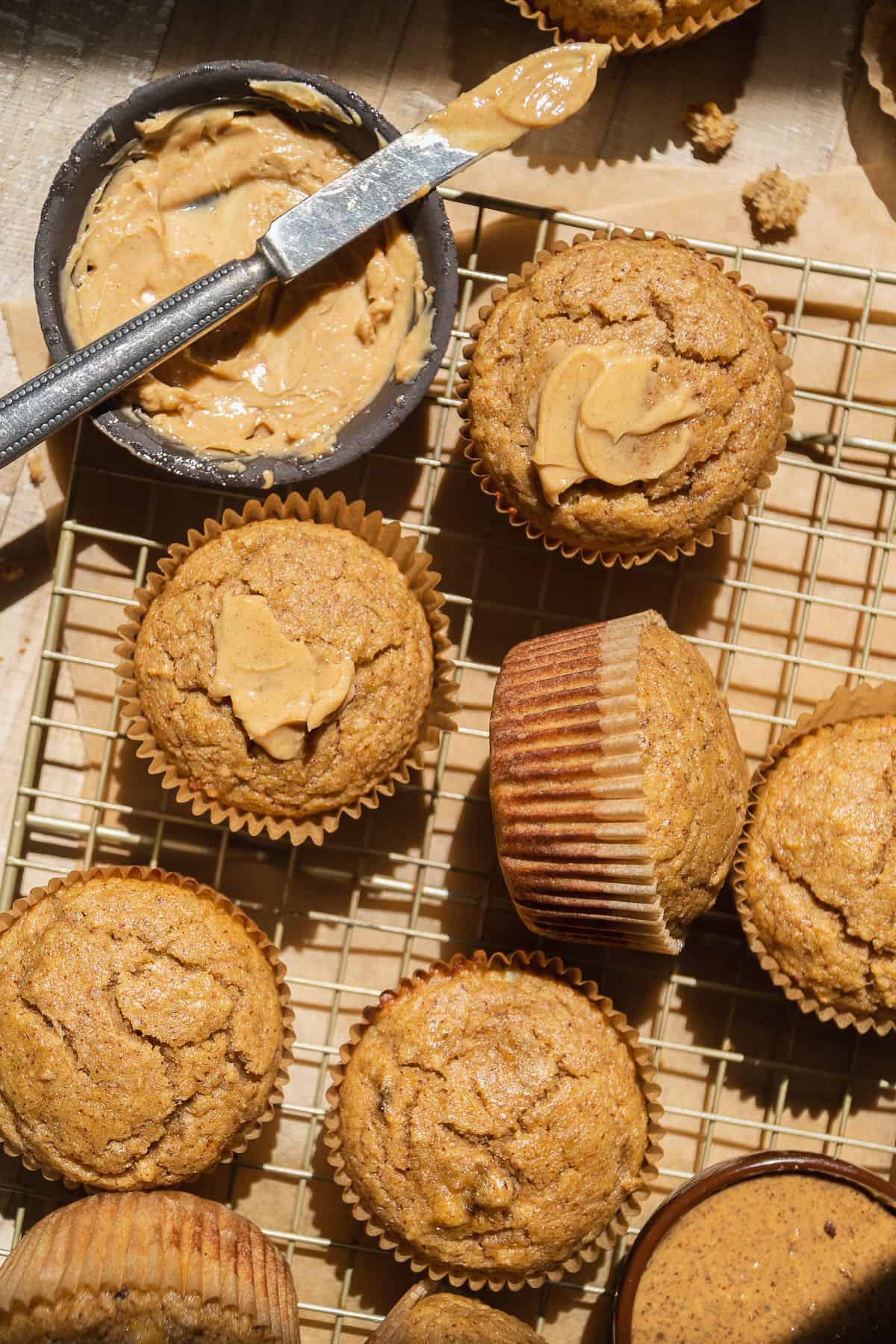 Peanut butter banana almond flour muffins scattered on a wooden surface.