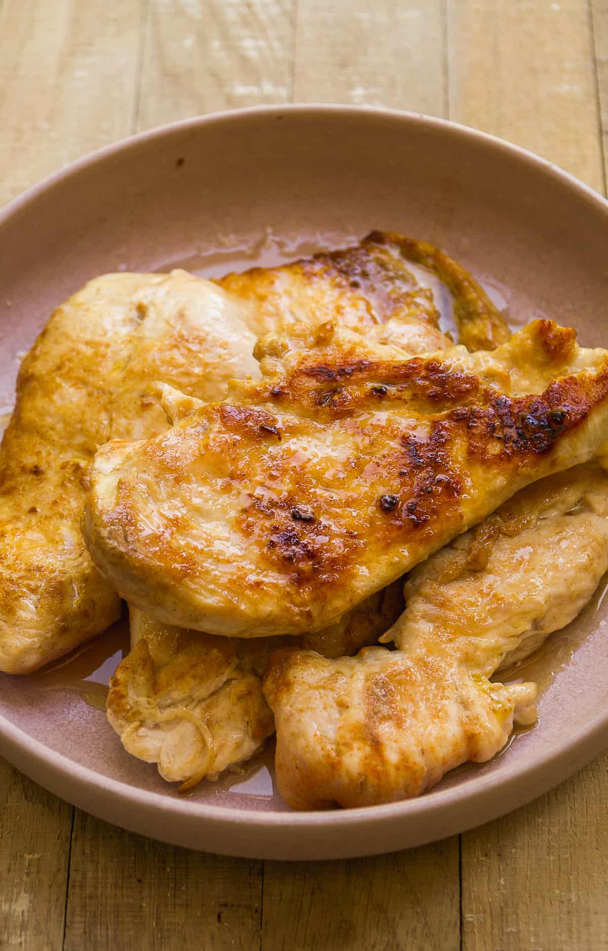 Cooked chicken breast piled up on a plate.