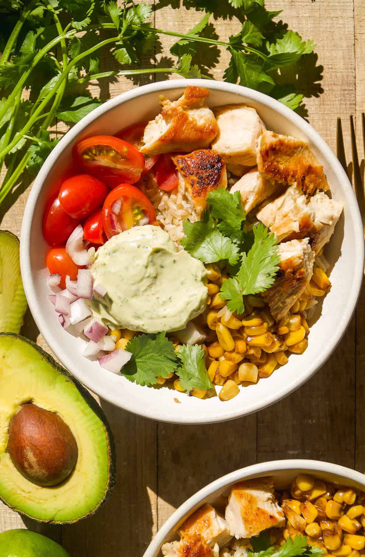 Overhead view of chicken taco bowls on a wooden surface.