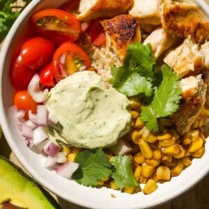 Chicken taco bowl with corn, tomatoes, and cilantro sauce.