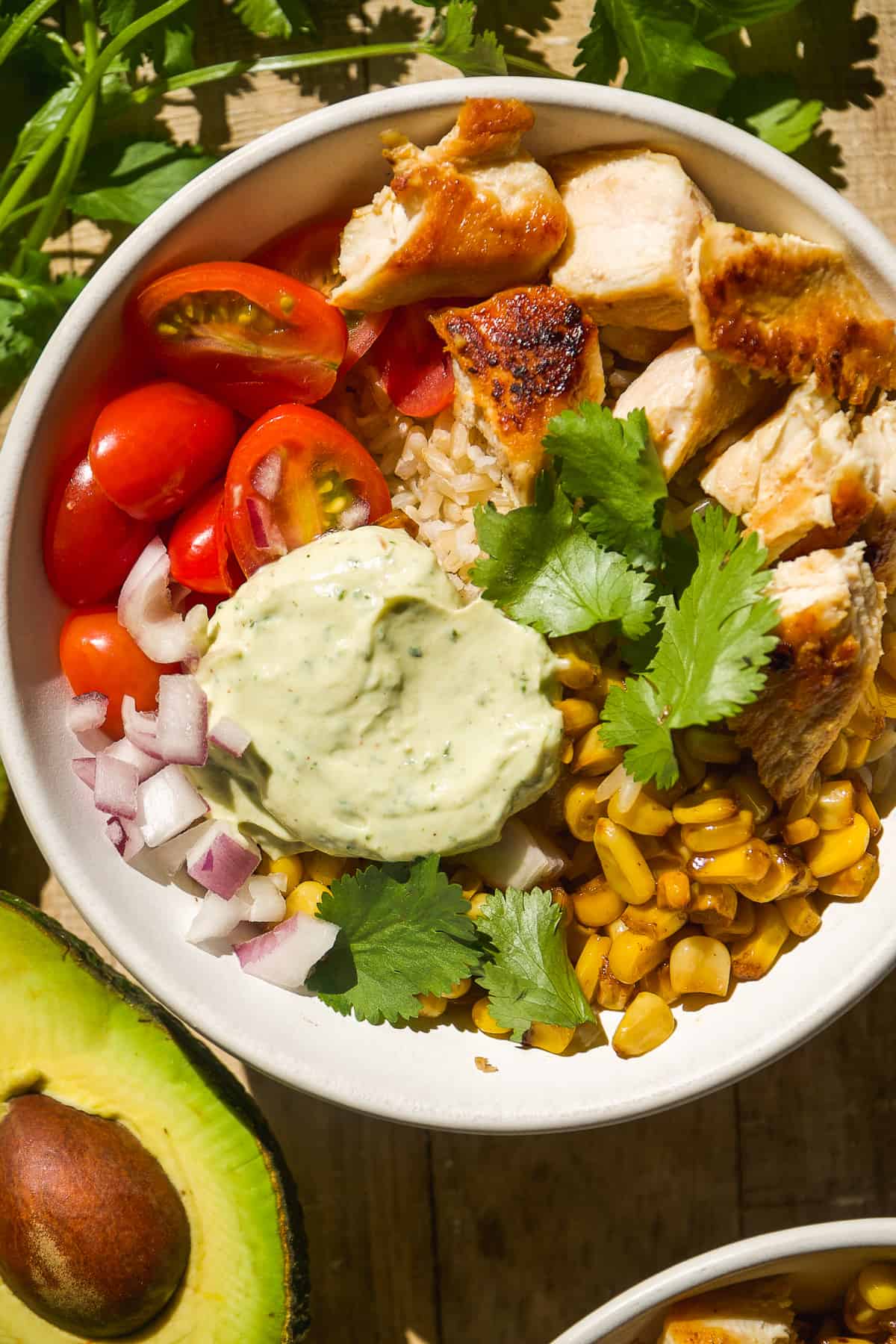 Chicken taco bowl with corn, tomatoes, and cilantro sauce.