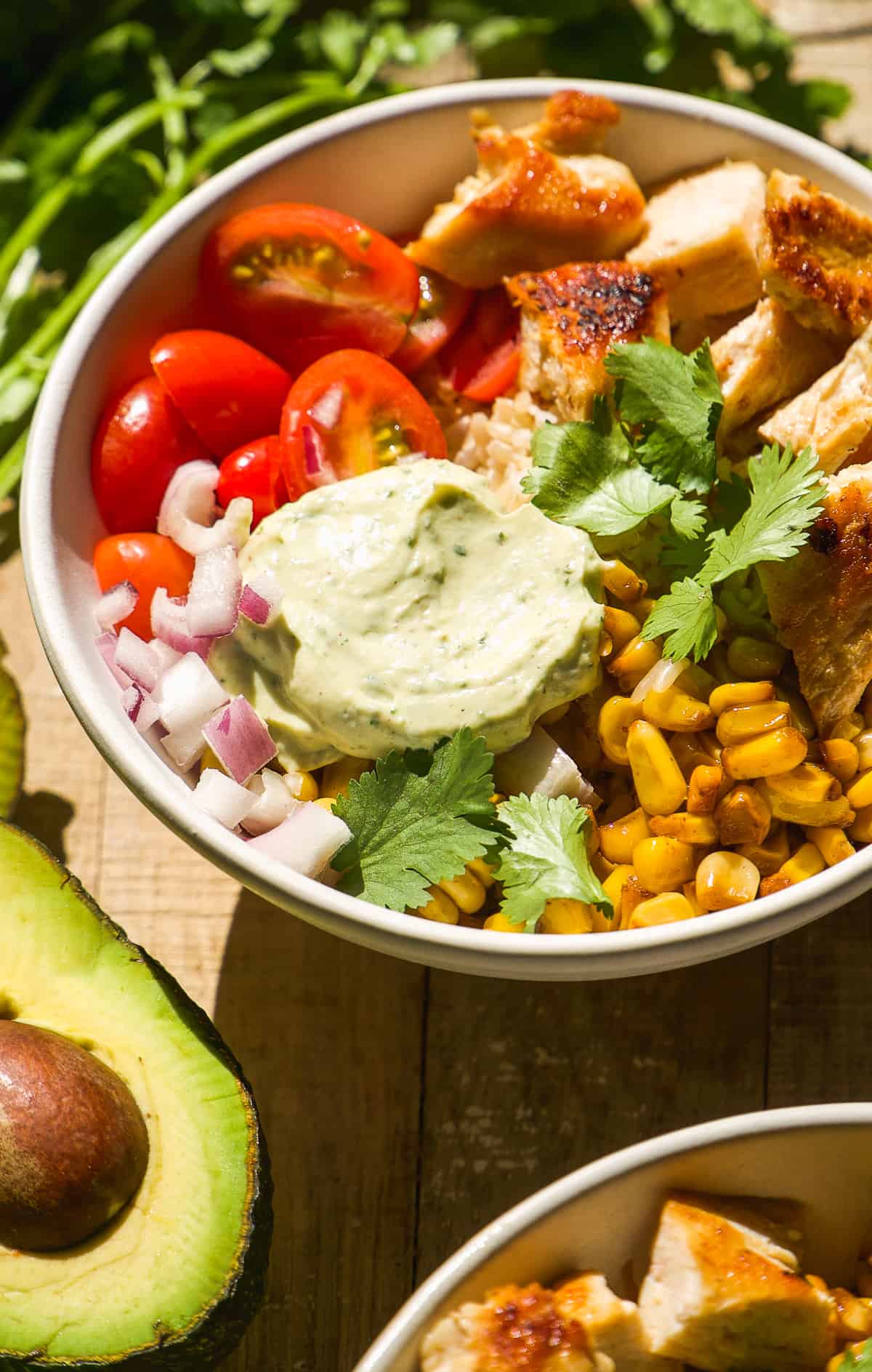 Taco bowl with chicken, corn, tomatoes, and cilantro avocado sauce.