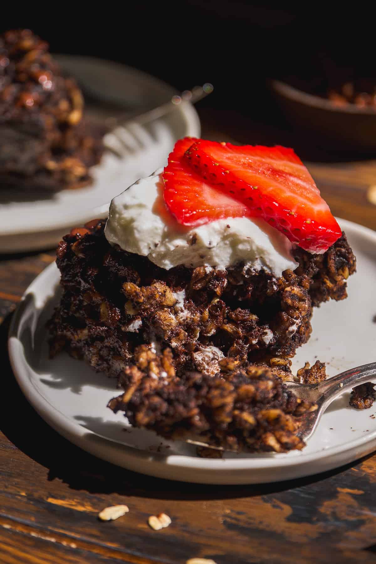 Chocolate baked oats on a plate with yogurt and strawberries on top.