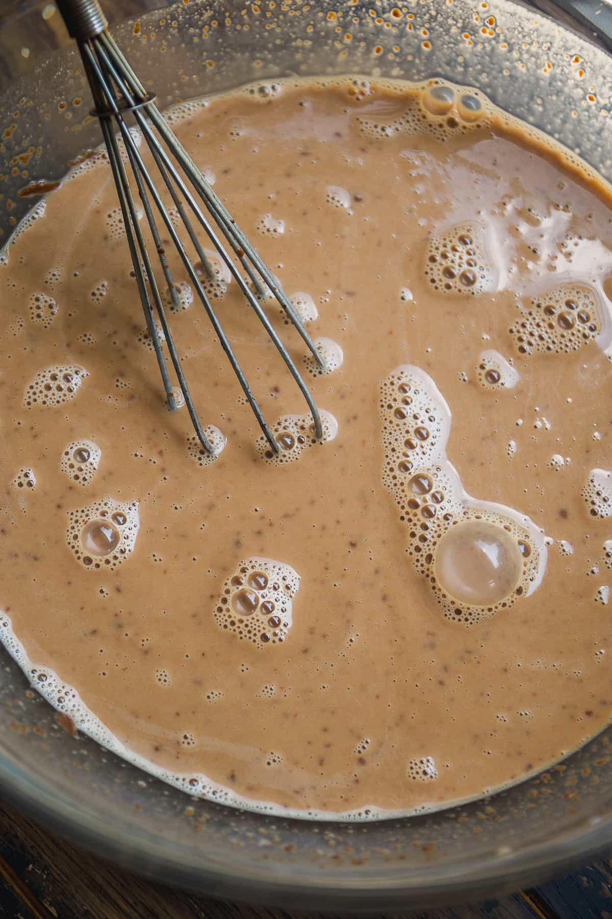 Chocolate oats ingredients on a glass bowl with a whisk.