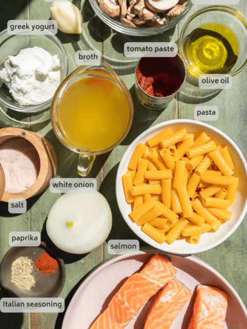 Creamy salmon pasta ingredients on a green surface.