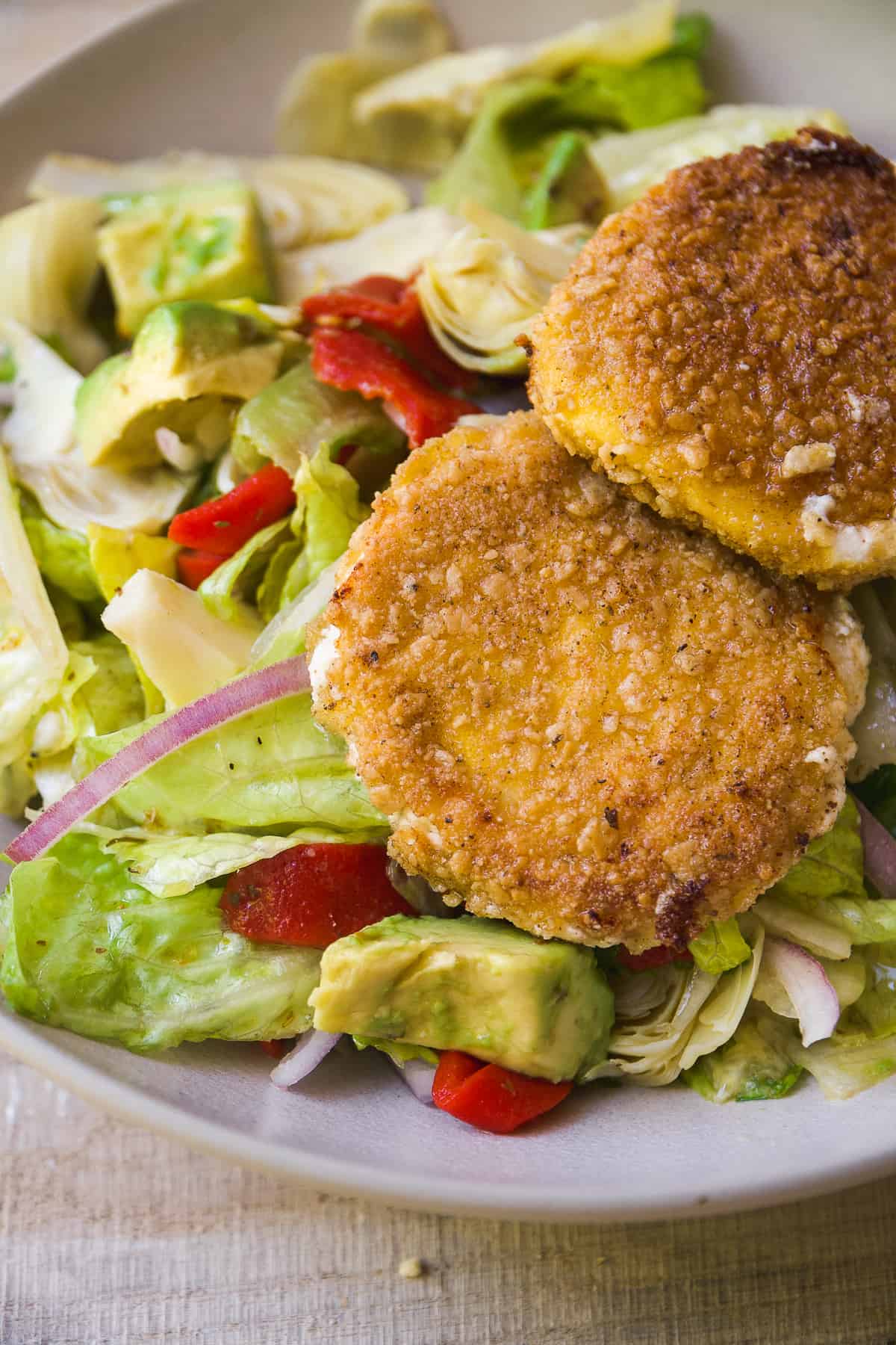 Salad tossed in dressing with two fried goat cheese patties.