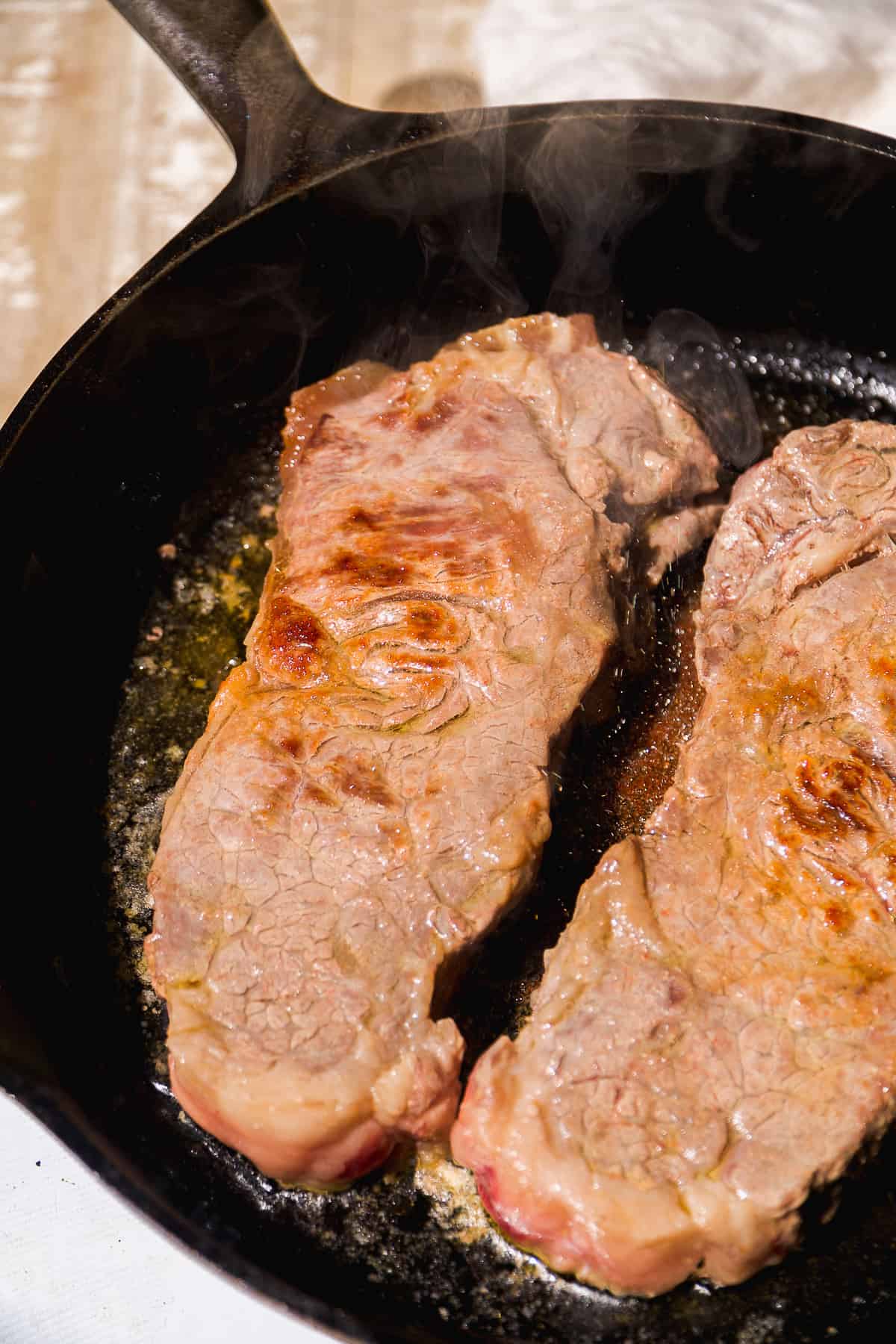 Steak cooking in a cast iron skillet.