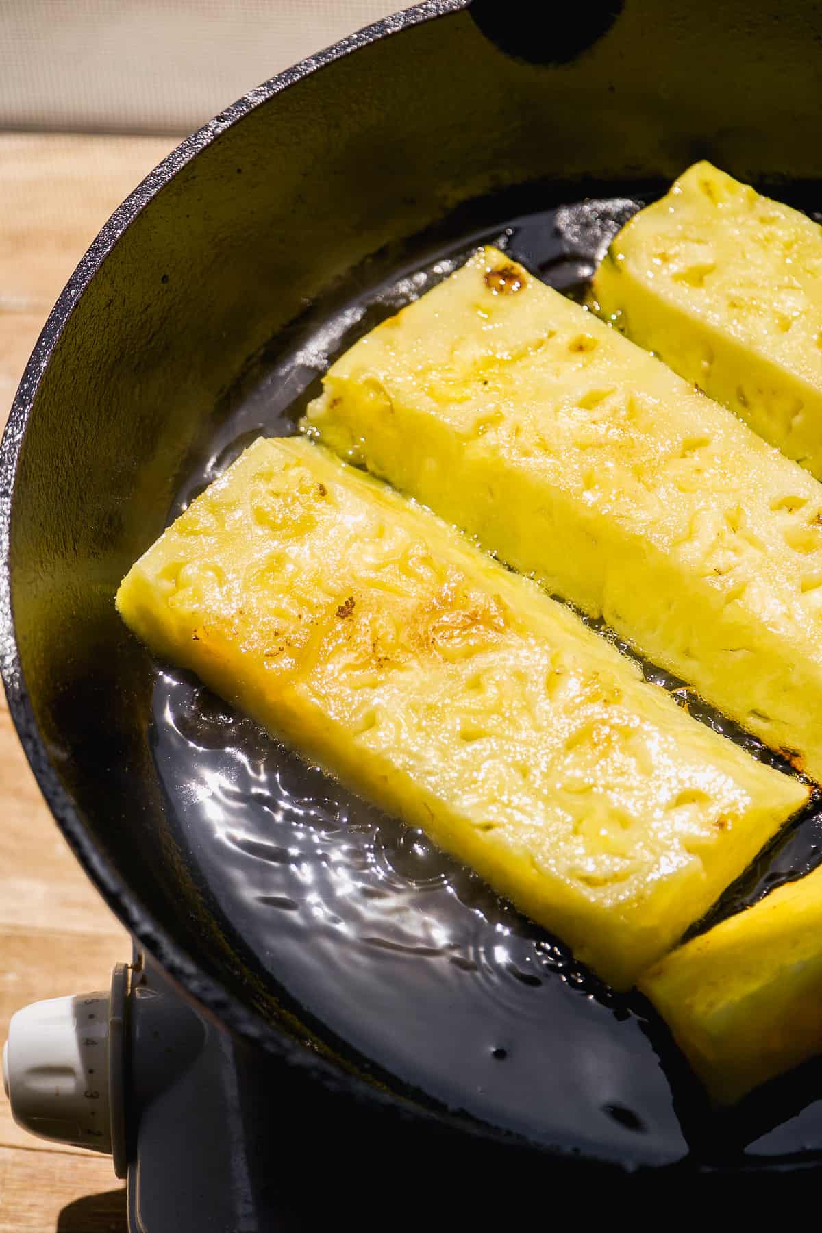 Pineapple roasting in a cast iron skillet.