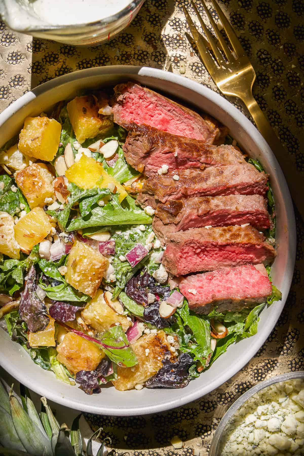 Gorgonzola salad with pineapple and strips of steak on top.