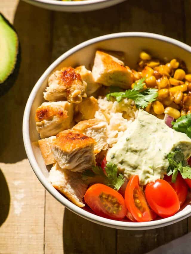 Chicken taco bowl with corn and tomatoes on a wooden surface.
