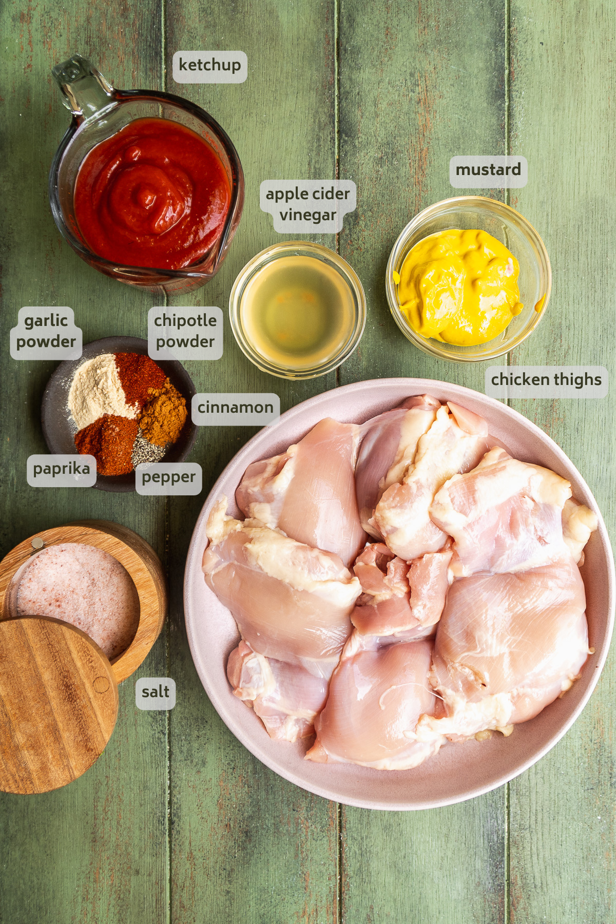 Baked bbq chicken thigh ingredients on a green surface.