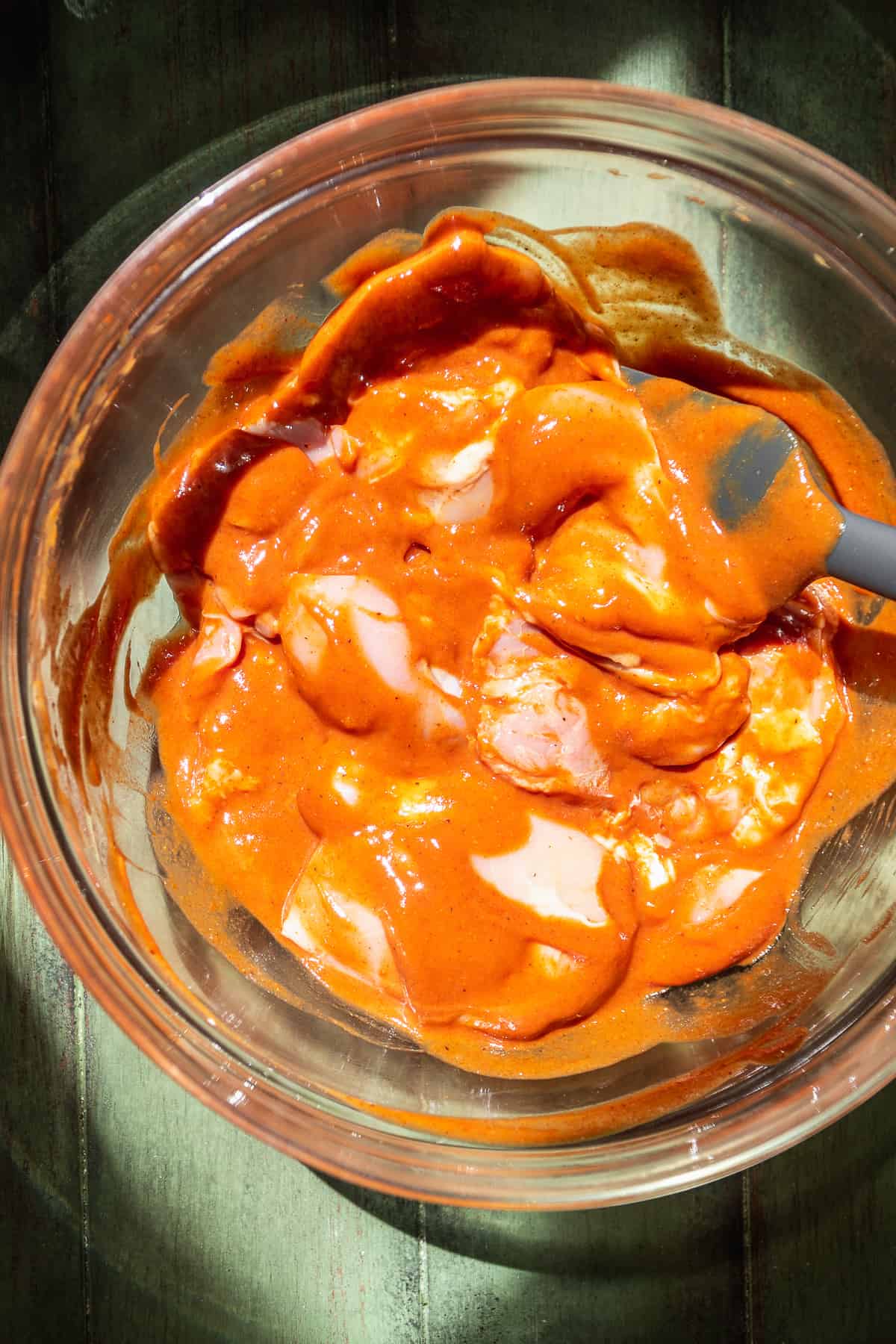 Bowl of chicken thighs coated in bbq sauce.