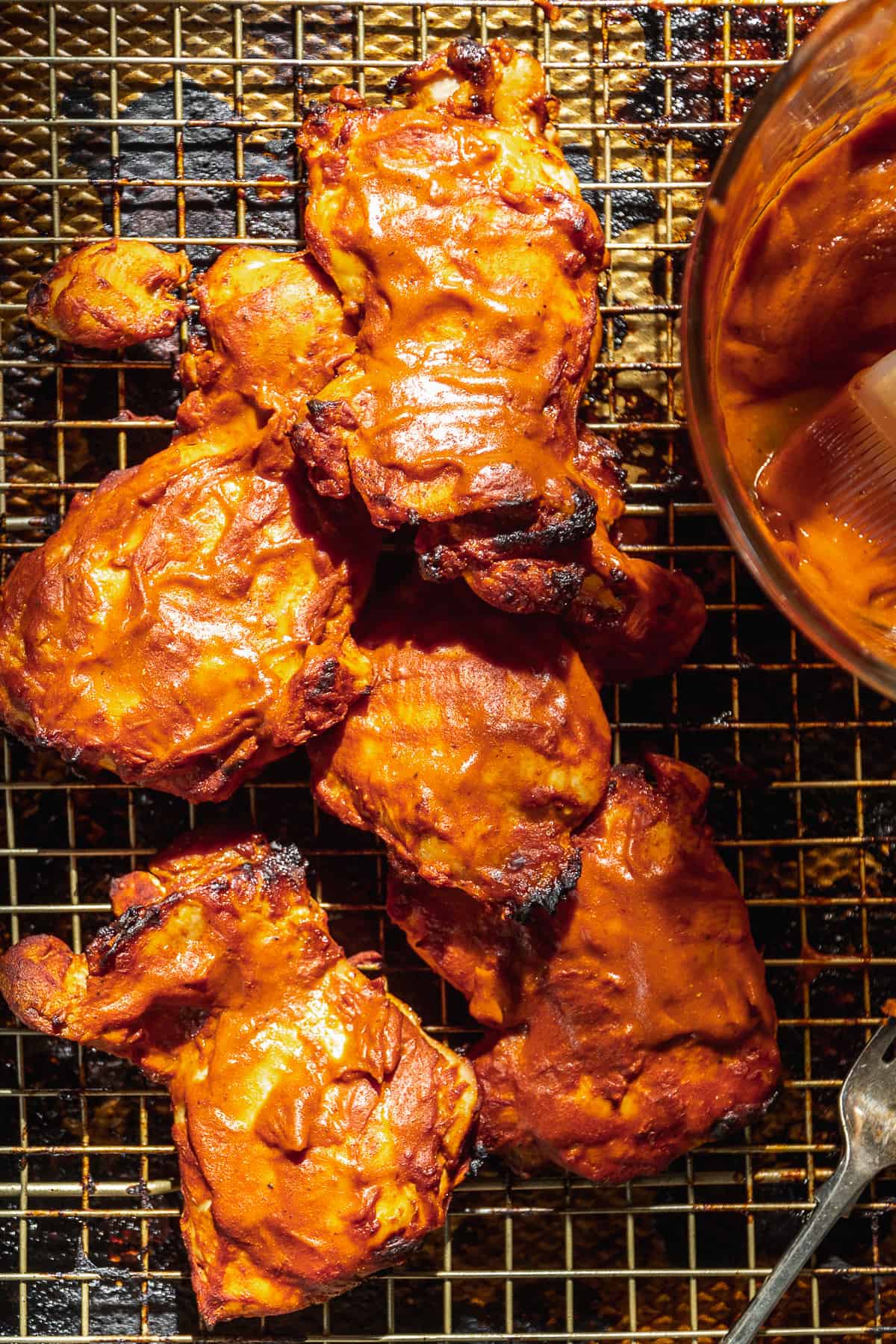 Barbecue chicken thighs with sauce on a wire rack.