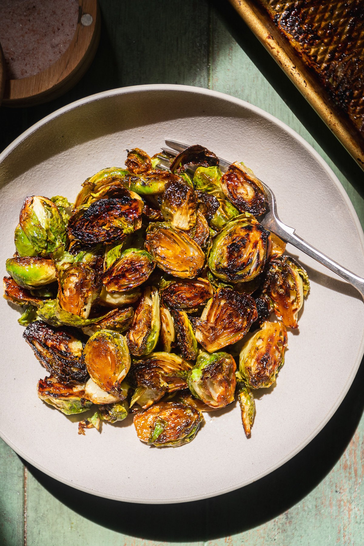 Caramelized brussel sprouts in a serving bowl with a fork.
