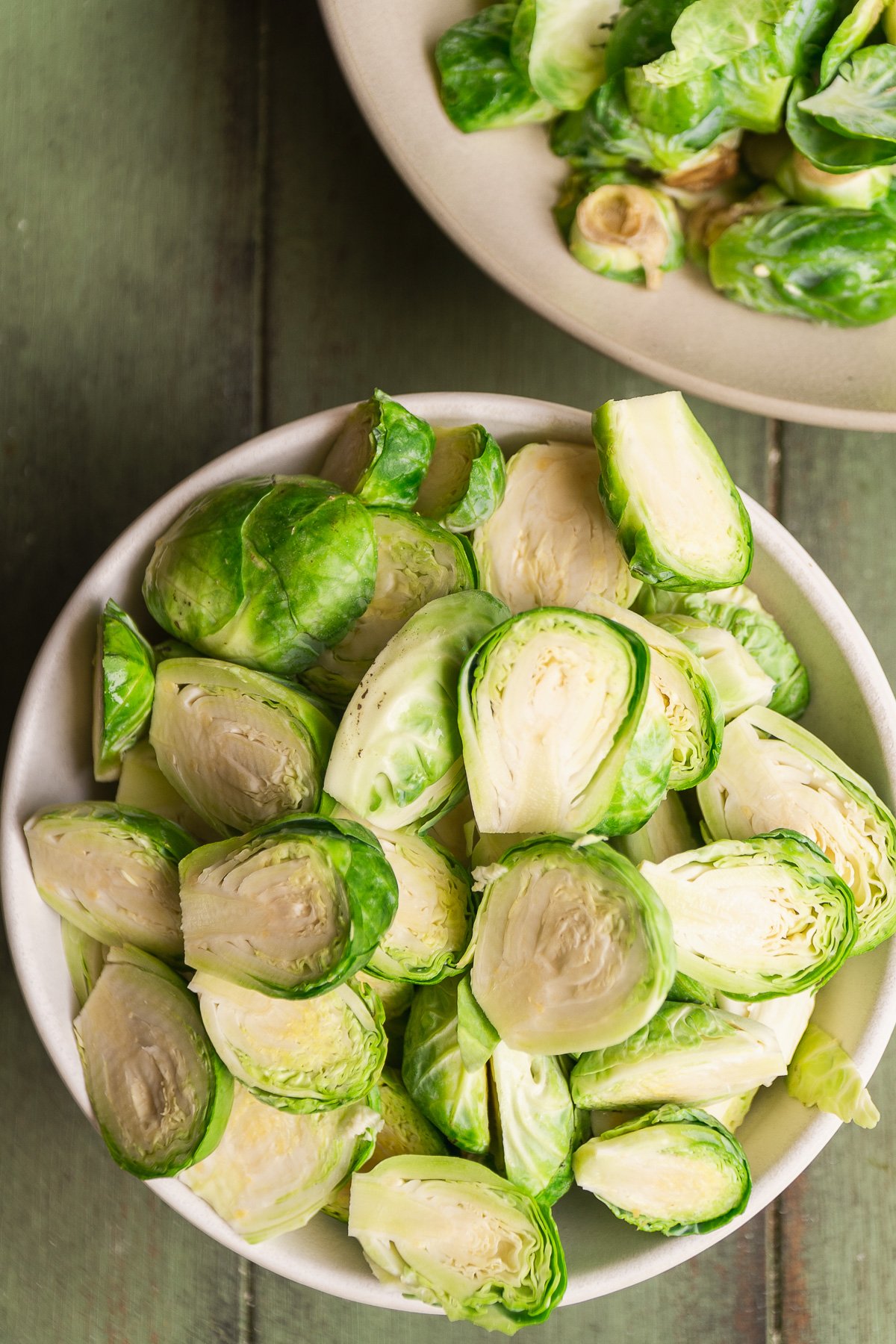 Brussel sprout halves in a white bowl.