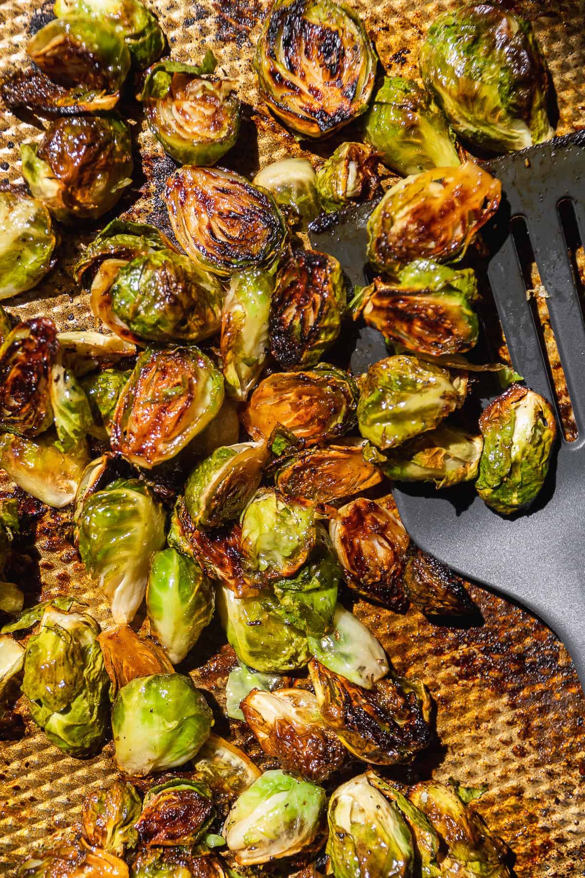 Roasted caramelized brussel sprouts on a gold baking sheet.