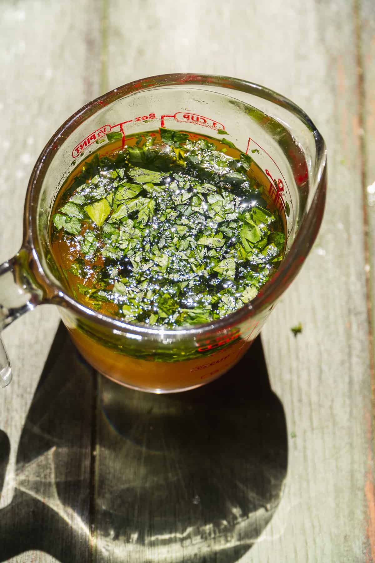 Olive oil parsley dressing in a measuring cup.