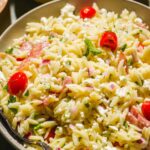 Lemon orzo pasta with tomatoes and salami.