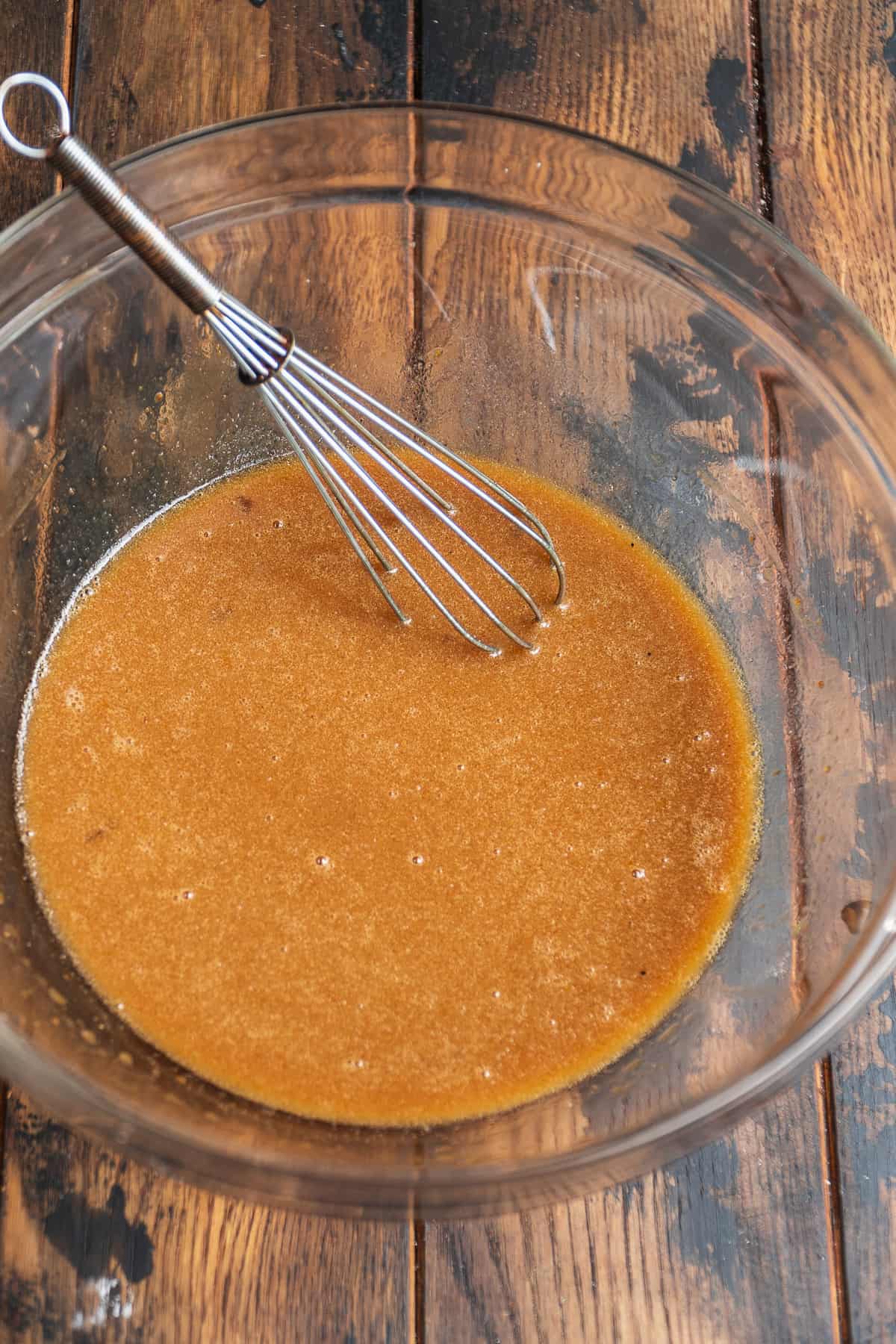 Wet ingredients mixed together in a large glass bowl with a whisk.