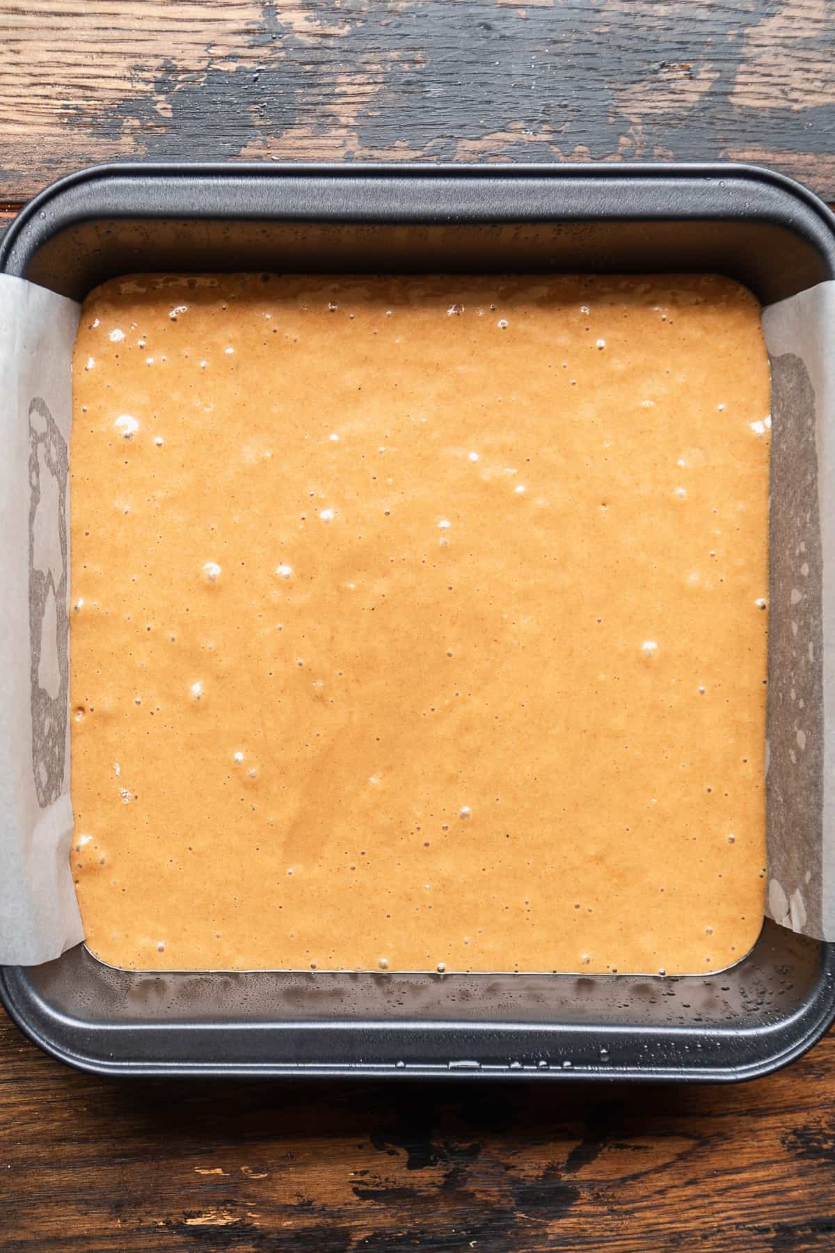 Oat flour cake batter in a square cake pan.