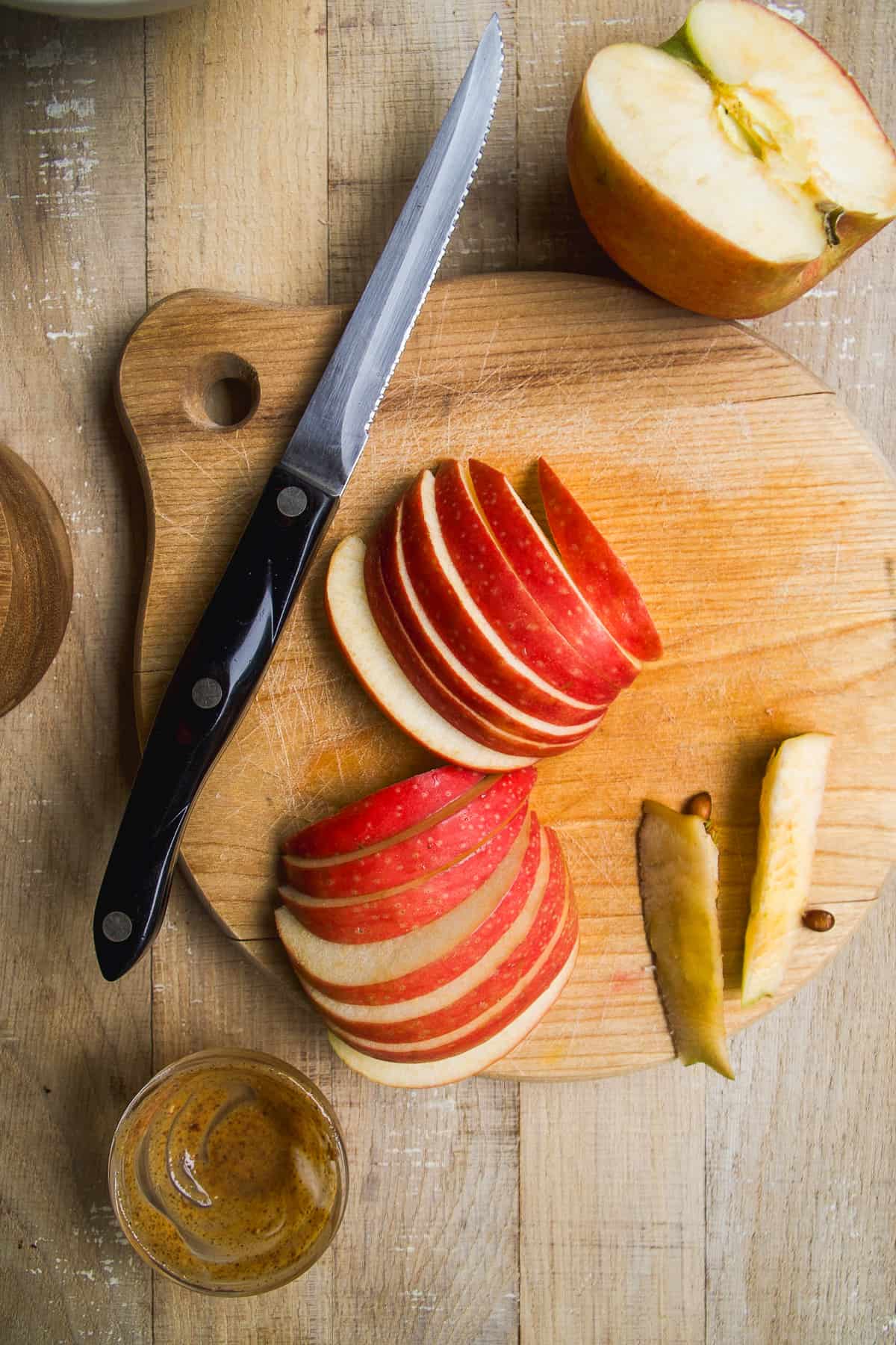 Apples cut into slices on a wooden cutting board.