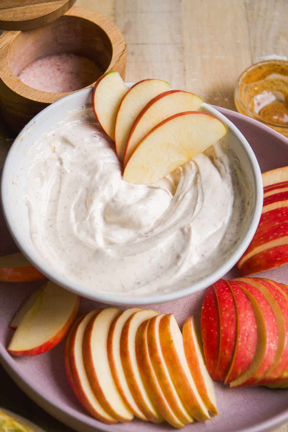 Almond butter yogurt fruit dip in a bowl with apples cut into slices.