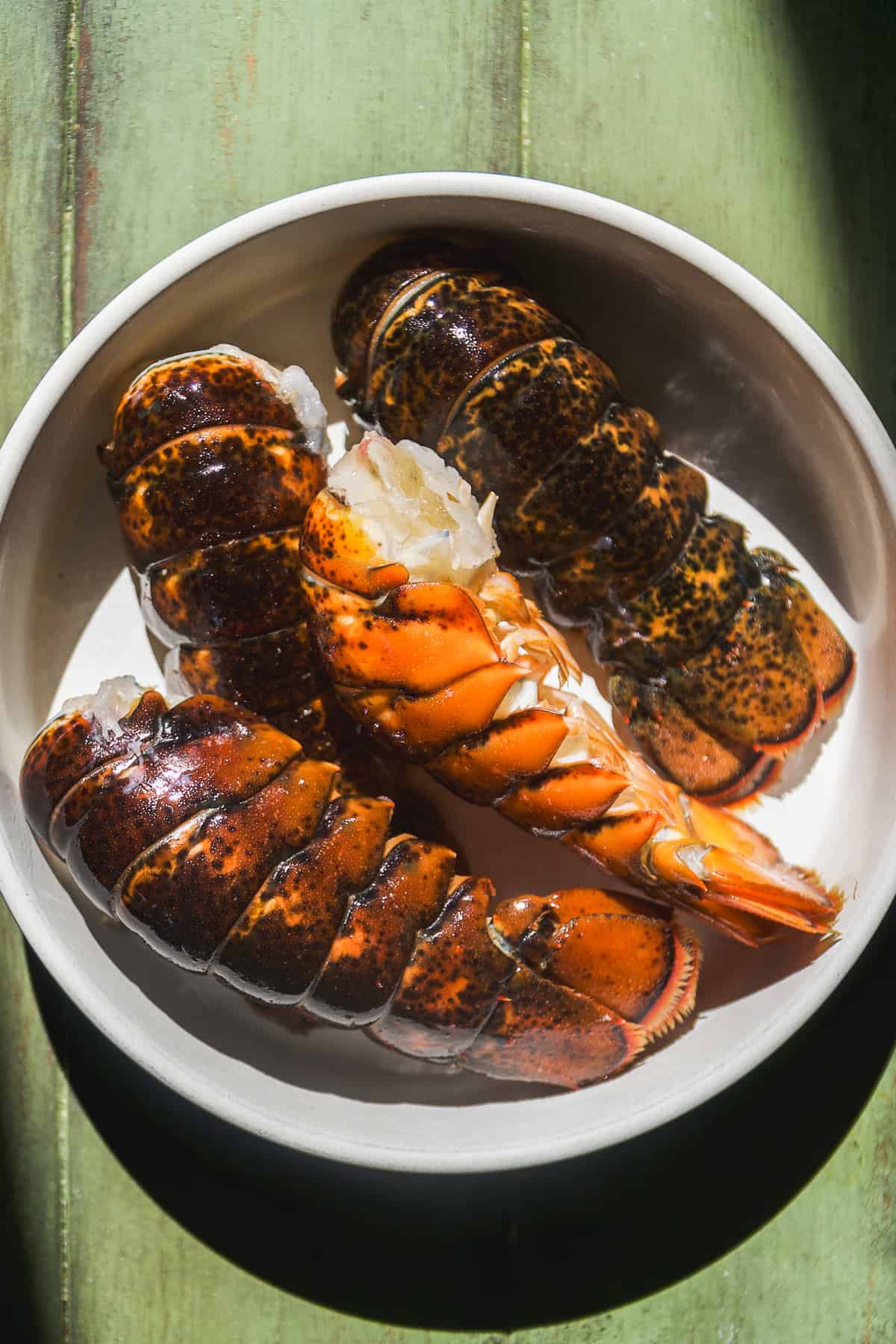 Lobster tails in the shells in a bowl.
