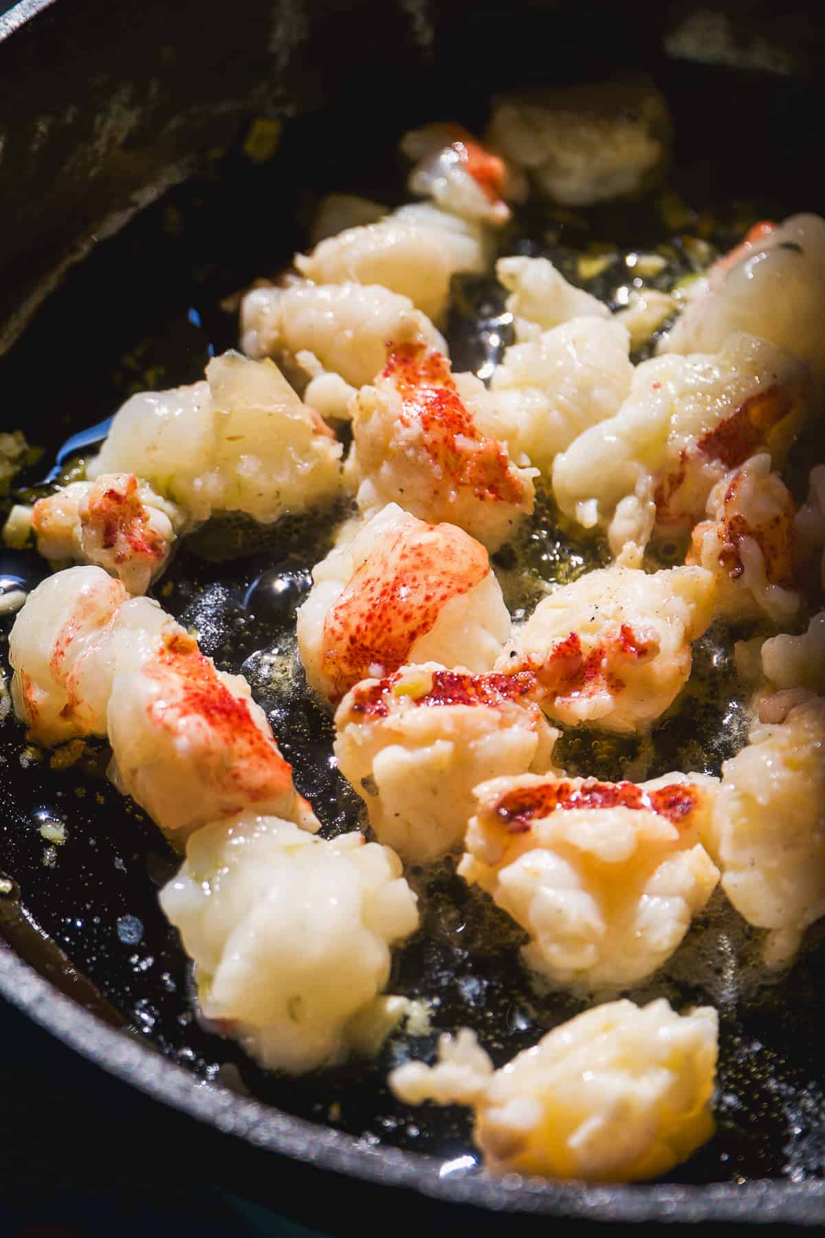 Lobster meat cut into pieces cooking in a skillet.