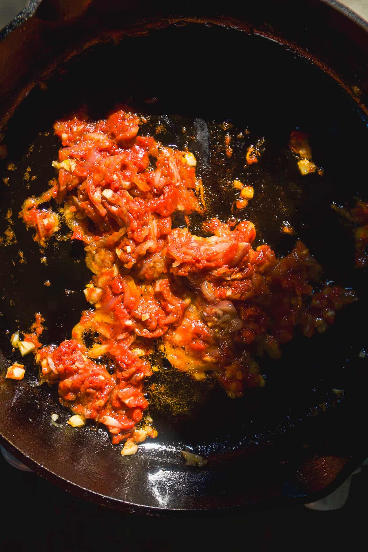 Tomato paste cooking in a cast iron skillet.