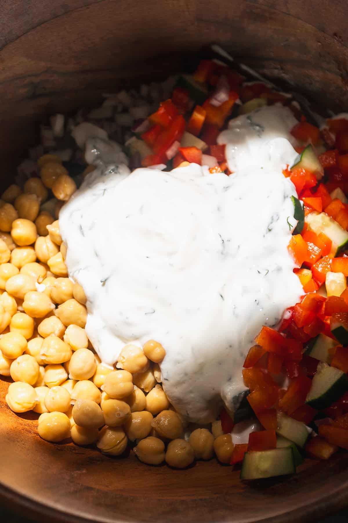 Chickpeas, cucumbers, and bell peppers about to be tossed in a greek yogurt dressing.