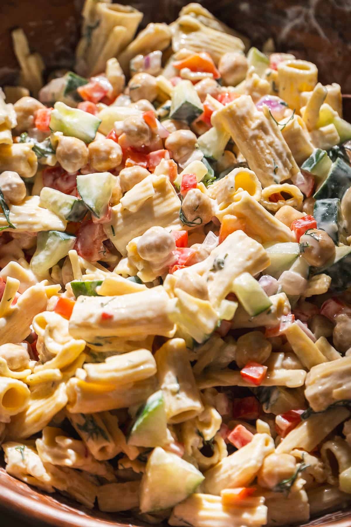 Pasta salad with noodles, chickpeas, cucumbers, and tomatoes.