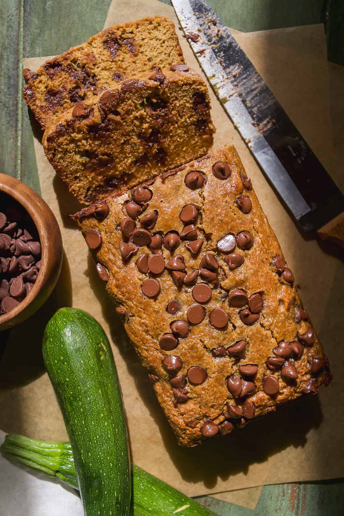Zucchini chocolate chip bread on parchment paper with a few slices cut out.