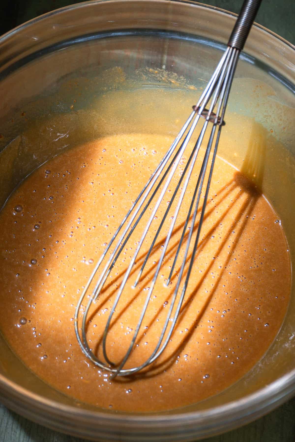 Wet ingredients for a zucchini bread whisked in a glass bowl.